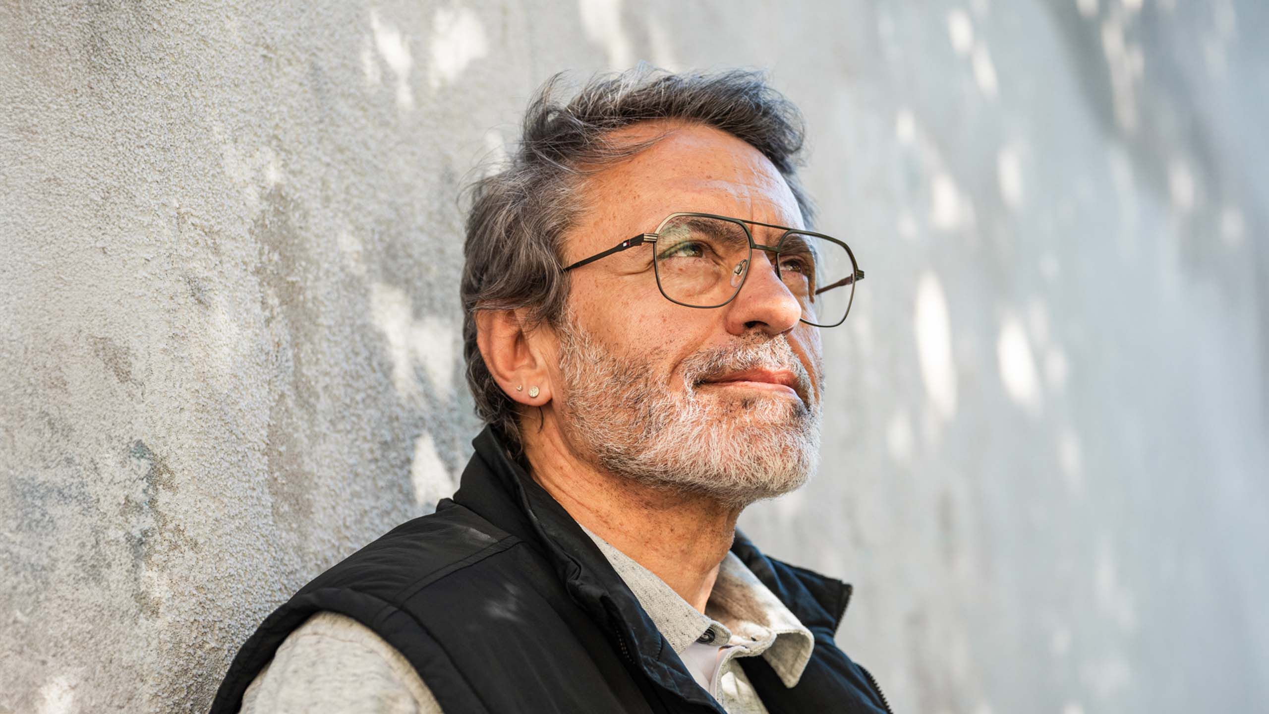 Silmälasit päässä oleva mies nojaa seinään